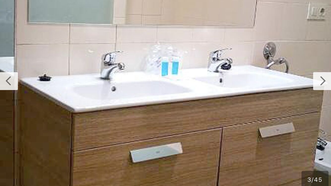 A bathroom with two sinks, a mirror, and wooden cabinetry.