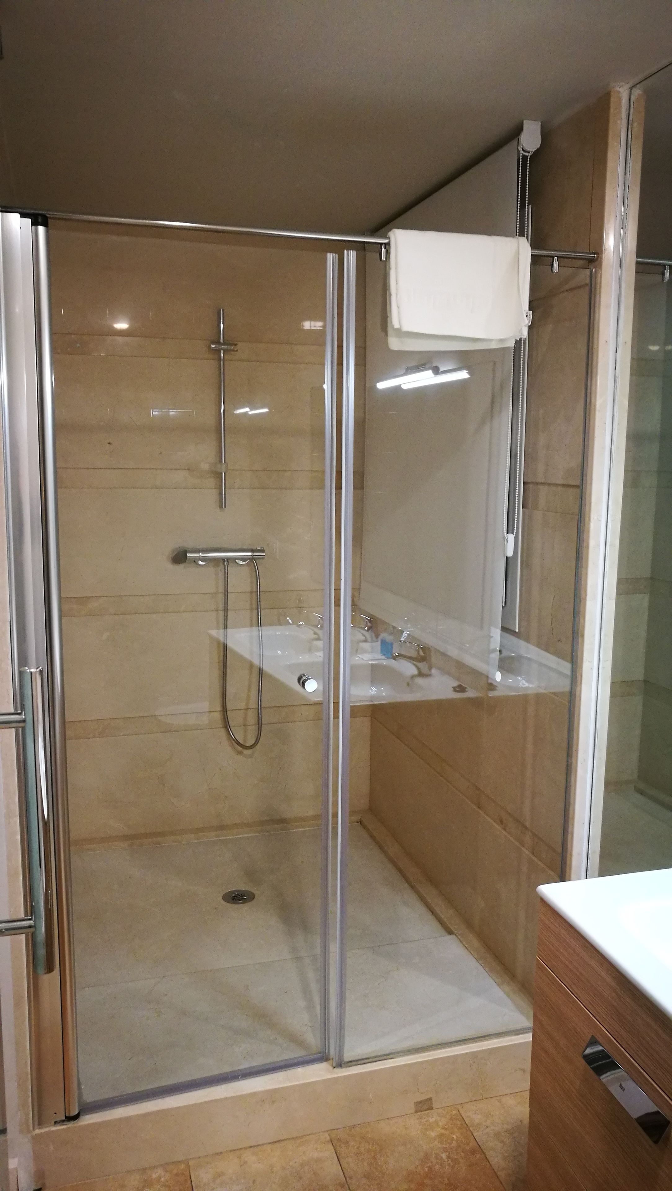 Un baño moderno con ducha de vidrio, tocador con espejo y lavamanos.