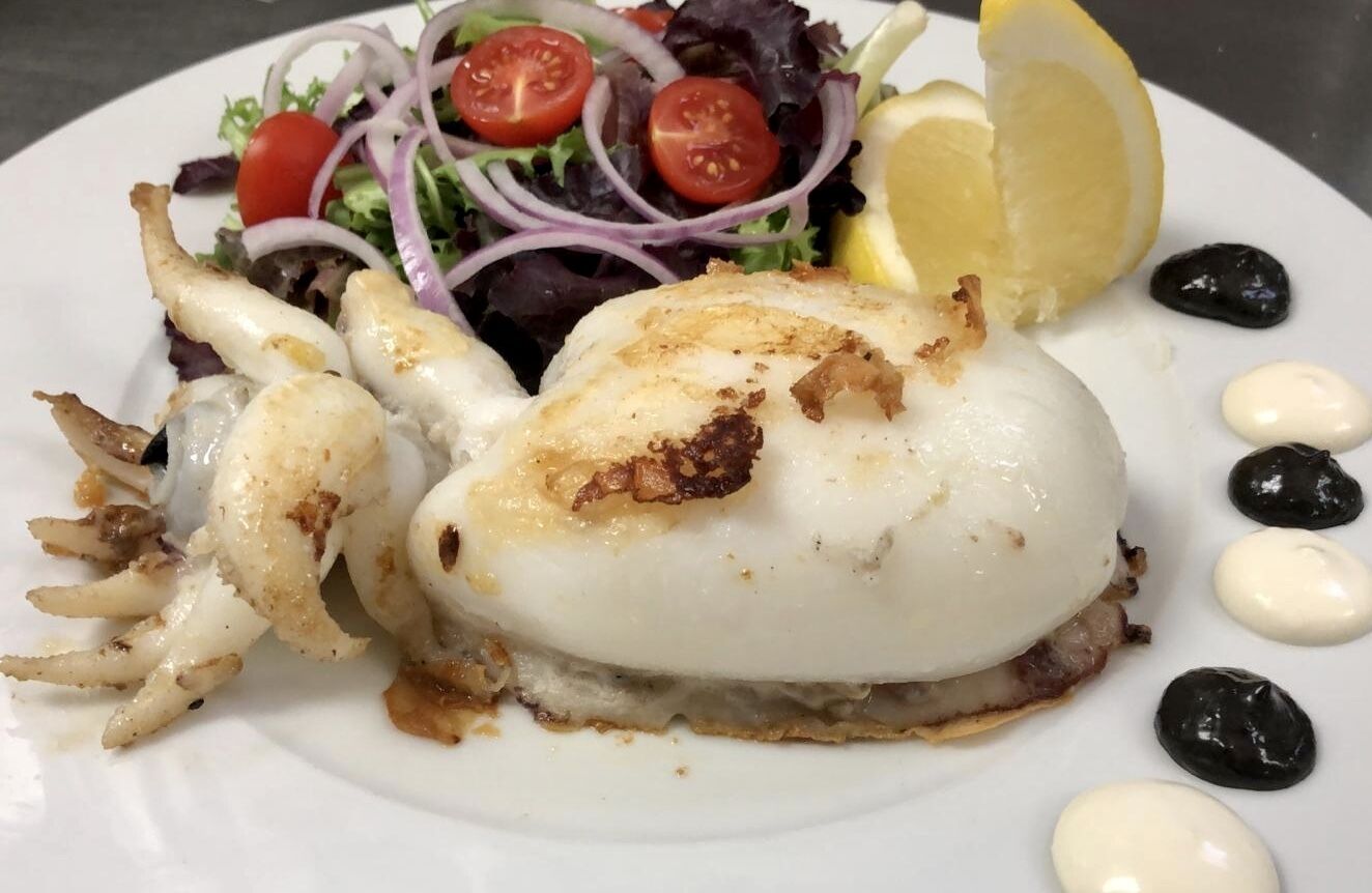 A plate with a seafood dish, a salad, and lemon slices.