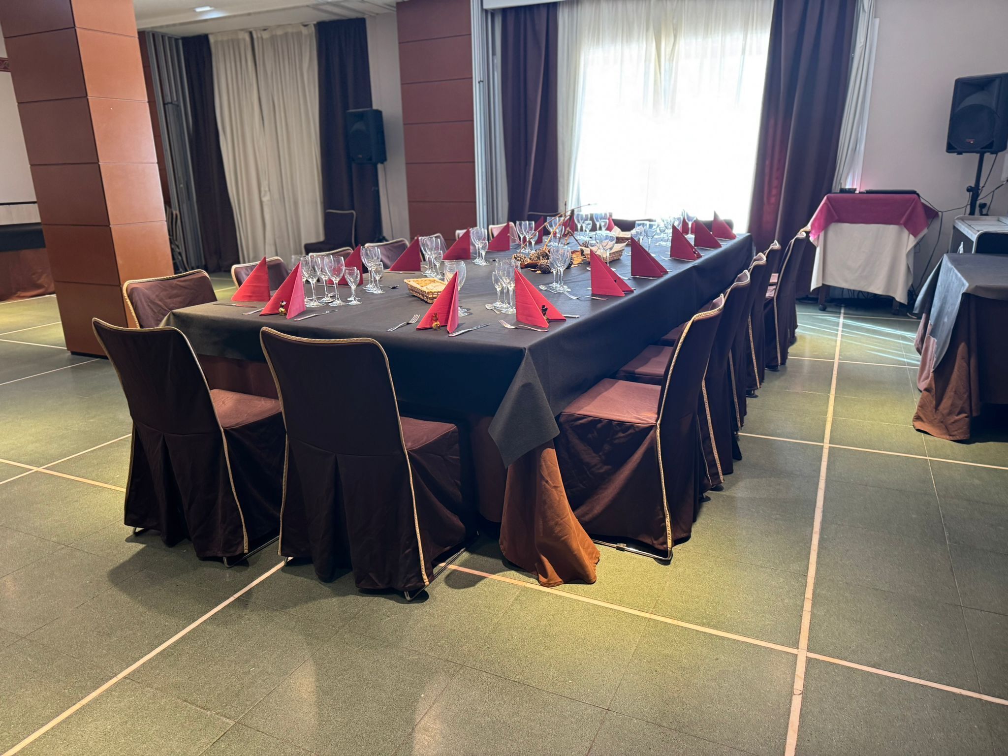 Un salón de conferencias con una larga mesa dispuesta para una reunión, equipado con sillas y cubiertos.