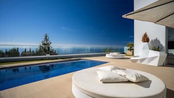 Alberca al aire libre, sombrillas en la alberca y camastros