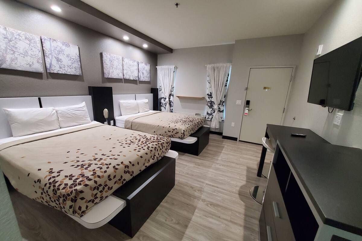 A hotel room with two beds, a TV, a desk, and a wardrobe.