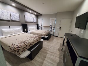 Une chambre d’hôtel avec deux lits, une télévision, un bureau et une armoire.
