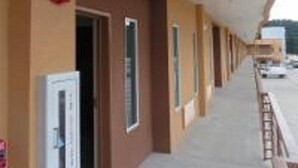 Un pasillo con puertas que dan a habitaciones, un detector de incendios y vista de coches estacionados afuera.