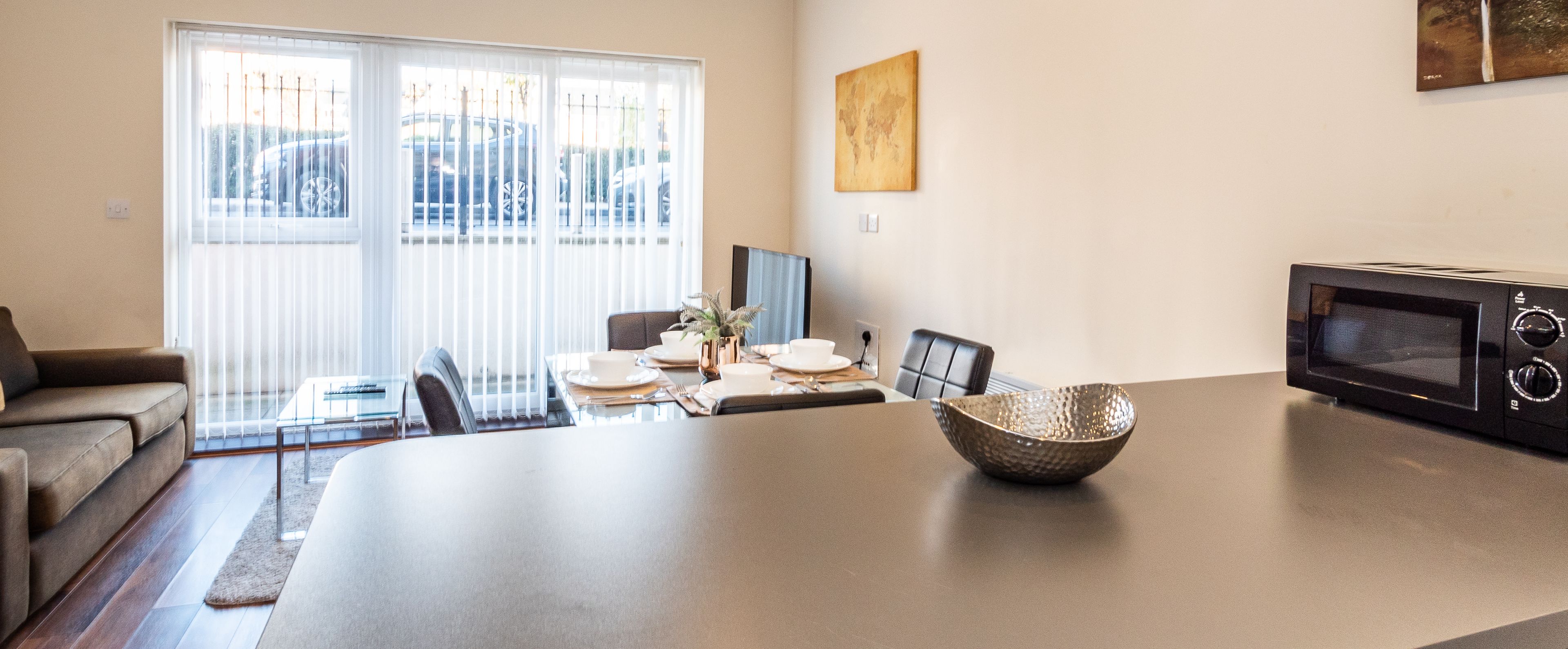 A modern living room with a dining area, a sofa, a coffee table, and a microwave.