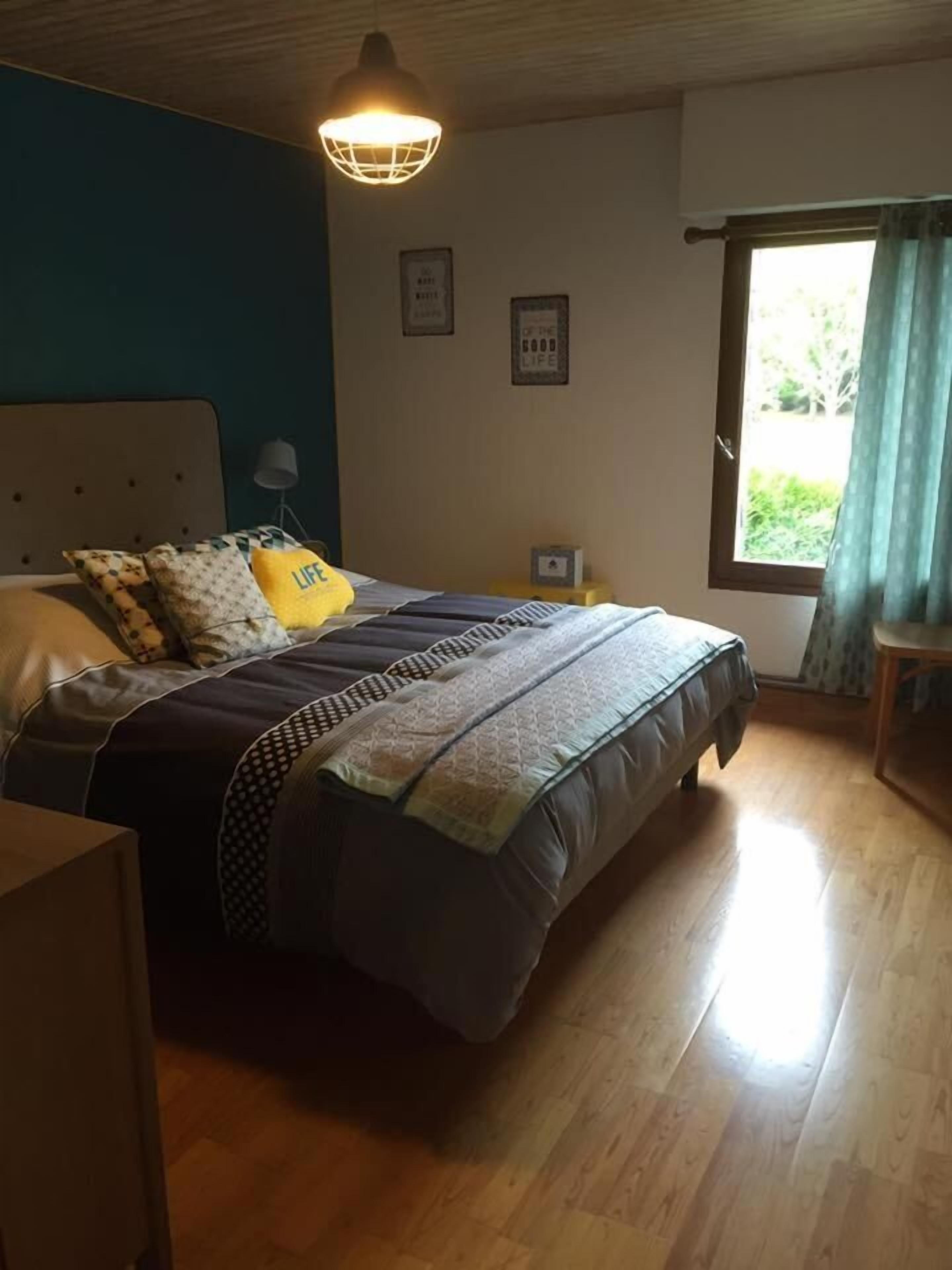 Una camera da letto con un letto, un comodino, una lampada e una finestra con tende.