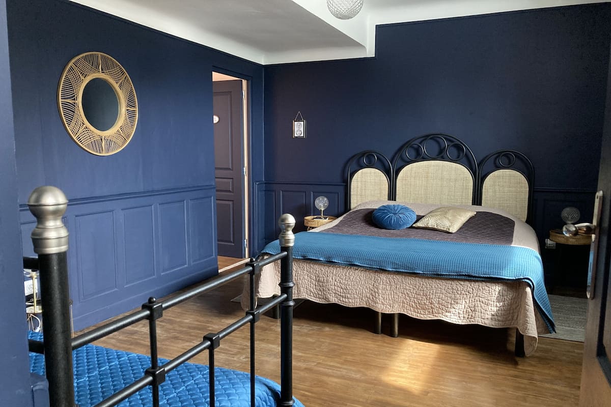 Um quarto com cama, mesa de cabeceira, penteadeira e espelho na parede.