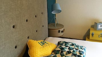 Un dormitorio con cama, mesita de noche, lámpara y almohadas decorativas.