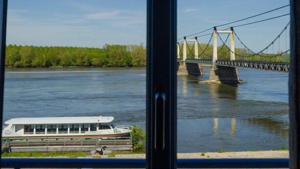 A view of a river with a bridge and a boat. - Hôtel Auberge de la Loire (Mauges-sur-Loire)