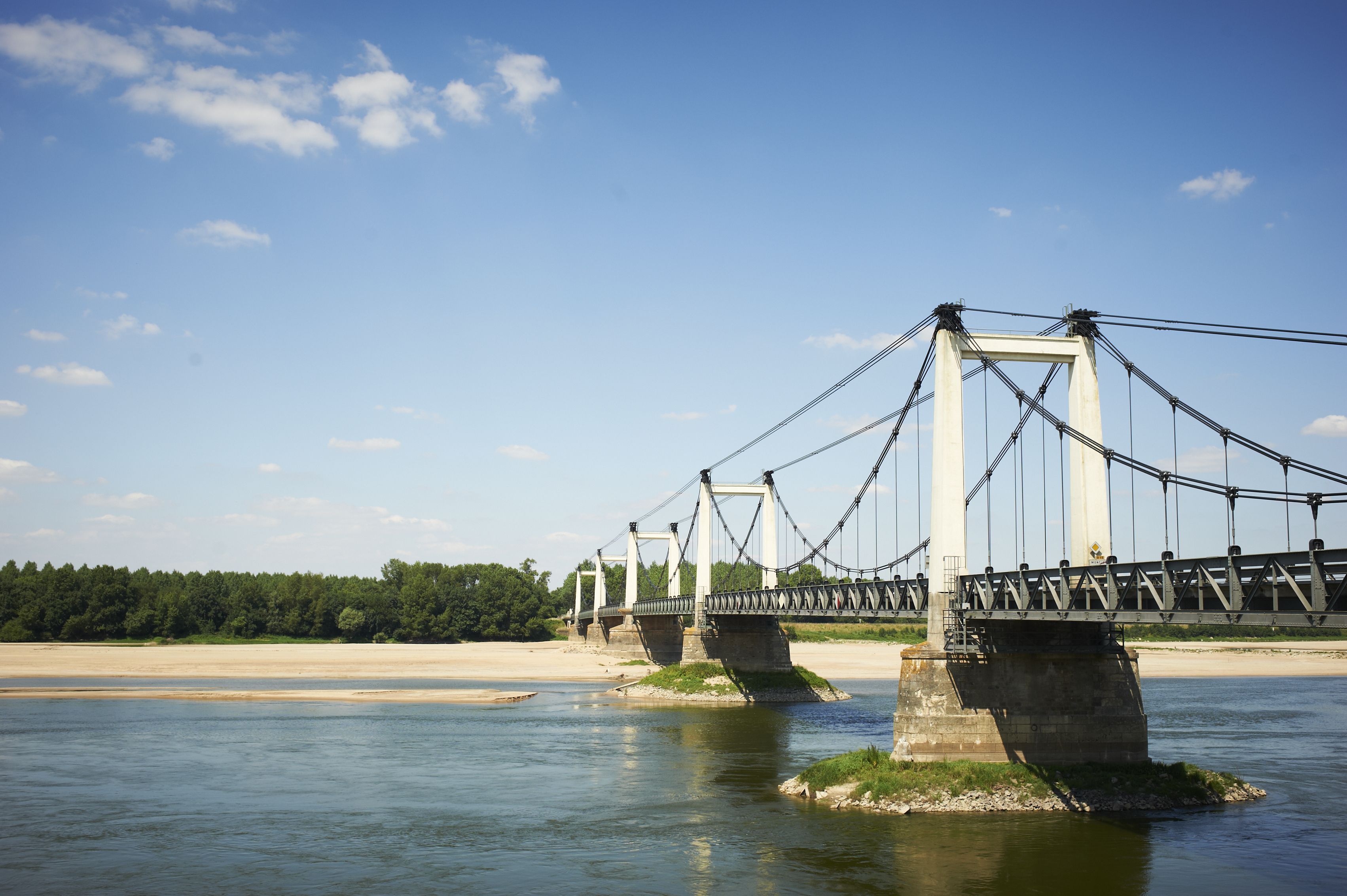 A suspension bridge over a river with concrete supports and cables.