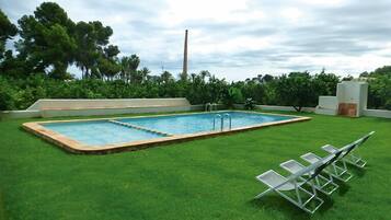 Een buitenzwembad, ligstoelen bij het zwembad