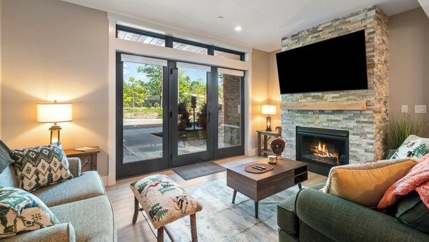 A modern living room with a fireplace, comfortable seating, and a large TV. - Cranmore Condominium Lodging (North Conway)