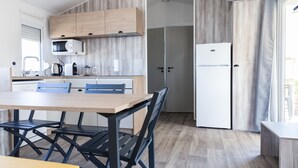 Eine moderne Küche mit Holzausstattung, einer Mikrowelle, einem Kühlschrank und einer Essecke mit Tisch und Stühlen.