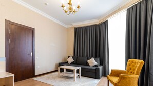 Ein Wohnzimmer mit einem dunkelblauen Sofa, einem gelben Sessel, einem Holztisch und einer Tür.