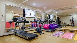 Ein Fitnessraum mit Laufbändern, Übungsbällen und einem großen Spiegel.