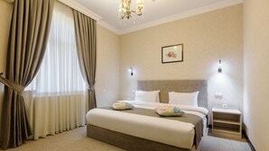 Ein Hotelzimmer mit einem großen Bett, einem Nachttisch, einer Wandlampe und einem Fenster mit Vorhängen.