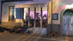 Um edifício com uma placa que diz 'L'ASINOVOLA' e uma entrada visível.