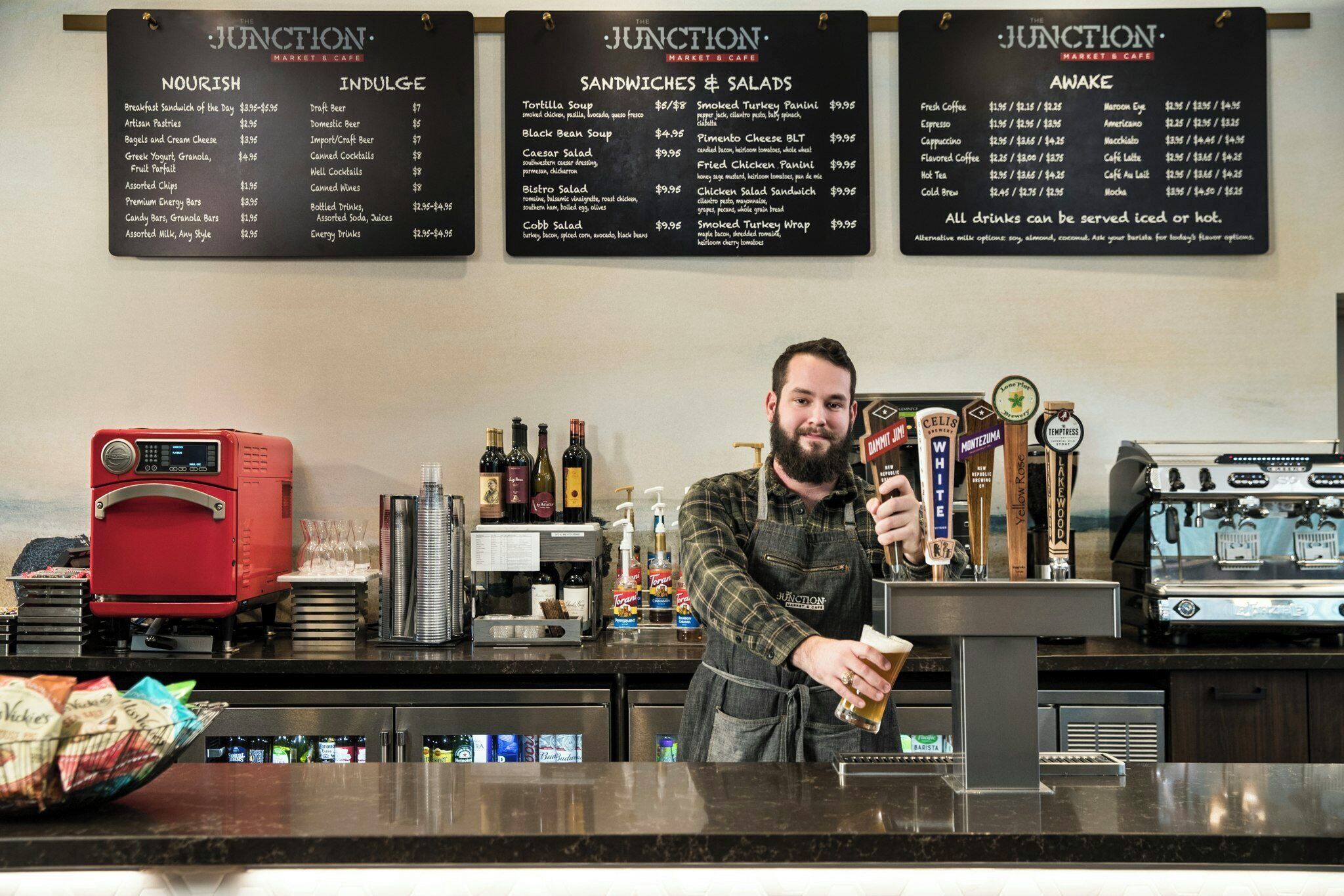 Un barista en una cafetería, con un menú que muestra diferentes opciones de comida y bebidas.