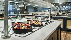 Een buffetgedeelte met verschillende stations, waaronder een fruitpresentatie en een vleeswarenbalie.