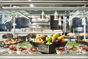 Buffet com diversas frutas e potes de iogurte.