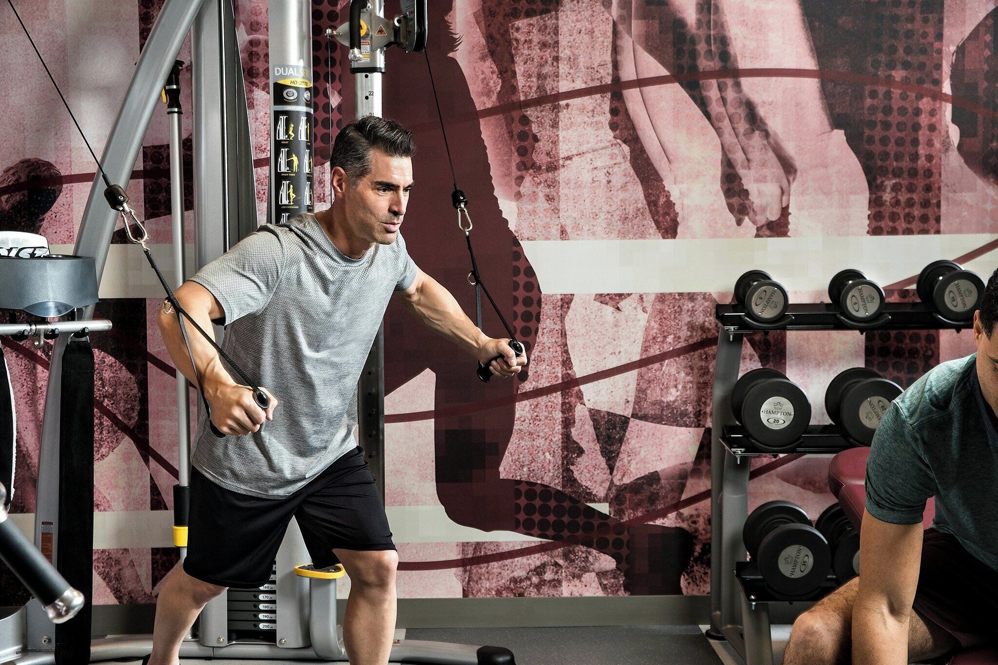 A gym with exercise equipment and a wall with a geometric pattern.