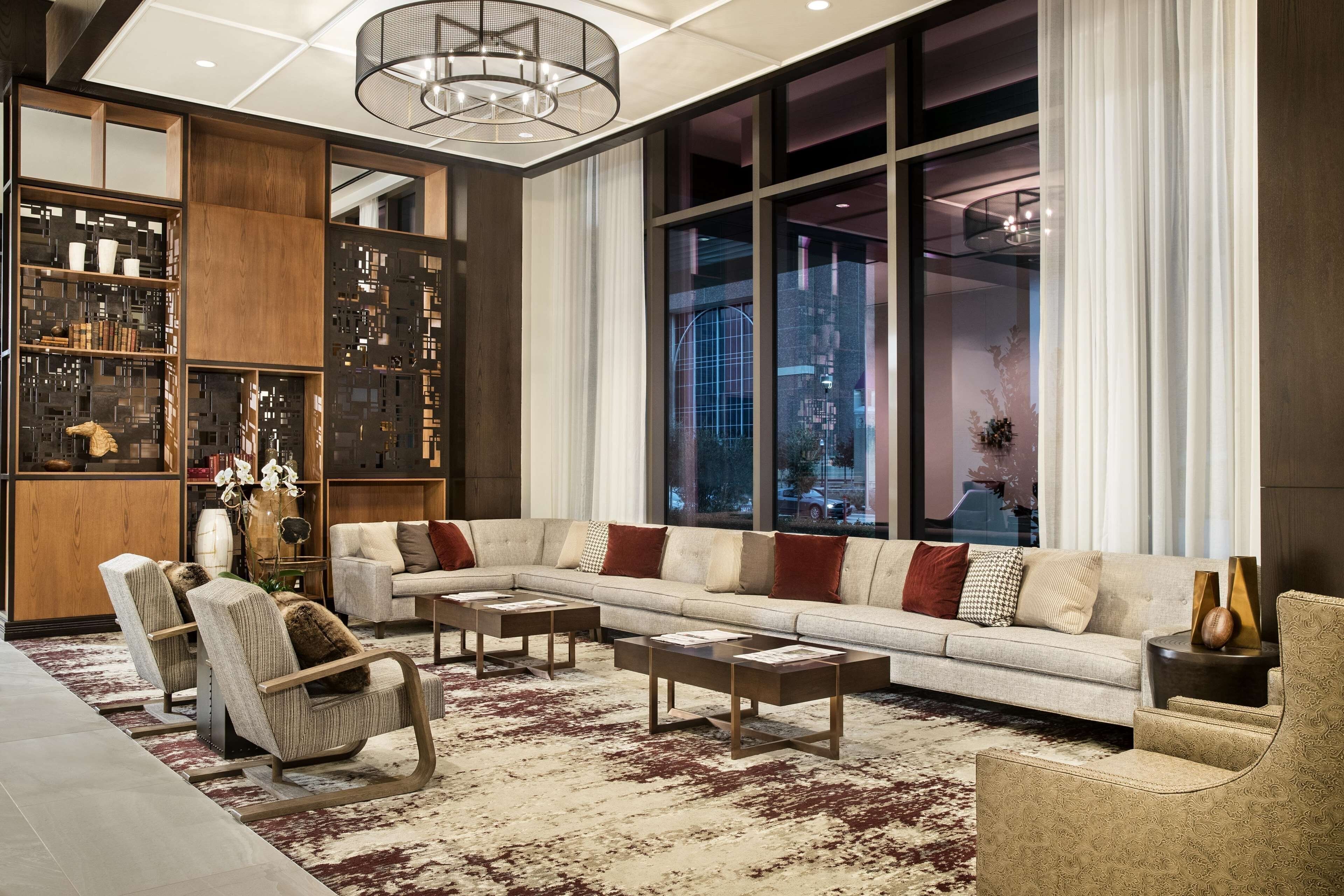 A modern living room with a sectional sofa, armchairs, a coffee table, and a bookshelf.