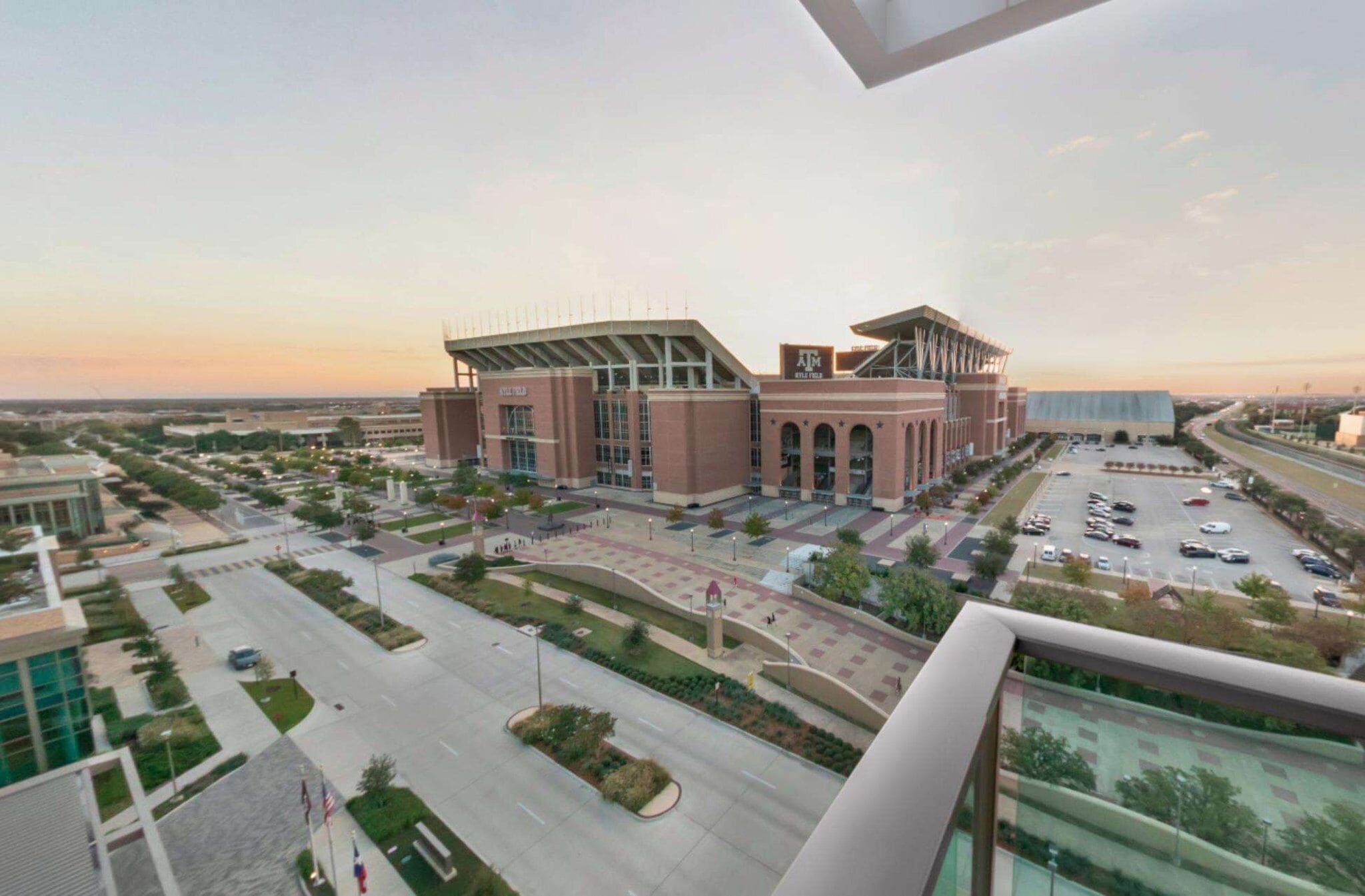 A stadium with a modern design, surrounded by a parking lot and a road.