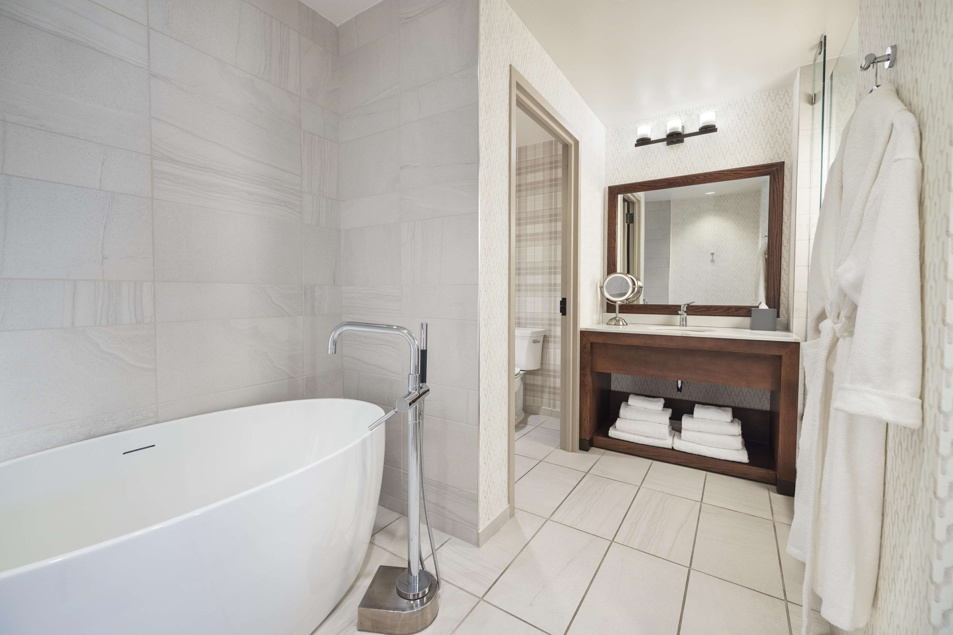 A modern bathroom with a freestanding bathtub, a vanity with a mirror, and a towel rack.