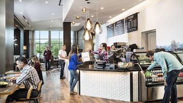 Interior moderno de cafetería con suelo de madera, iluminación colgante y un panel de menú.