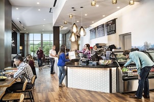 Um café moderno com chão de madeira, iluminação pendente e um quadro de menu.