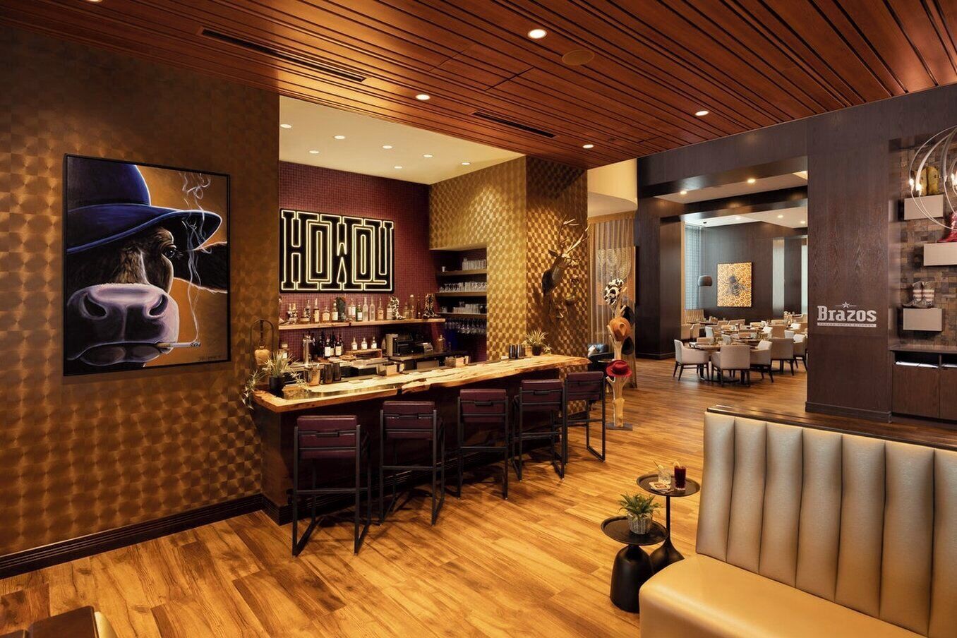 A bar area with a wooden ceiling, a bar counter with stools, and a wall with a large 'HOKU' sign.