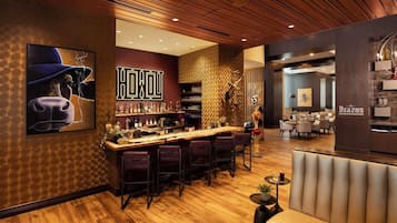 A bar area with a wooden ceiling, a bar counter with stools, and a wall with a large 'HOKU' sign.