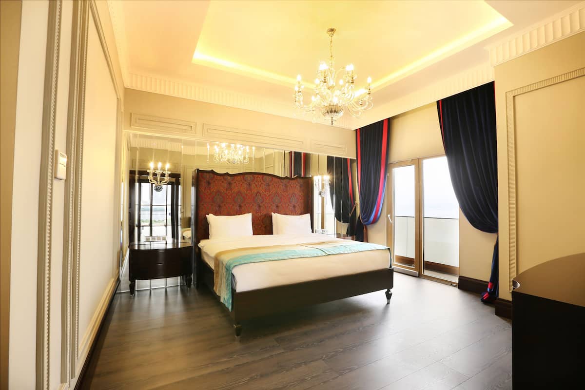 A spacious bedroom with a large bed, a chandelier, and a view of the outdoors.