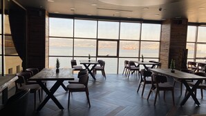 A modern dining area with large windows offering a view of a body of water and distant land. - TRYP by Wyndham Izmit (Basiskele)