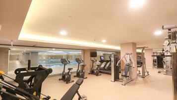 Un gimnasio bien iluminado con diferentes equipos de ejercicio, incluyendo cintas de correr, bicicletas estáticas y máquinas de pesas.