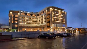 Un hôtel moderne à plusieurs étages, doté d’un parking et d’une façade bien éclairée.