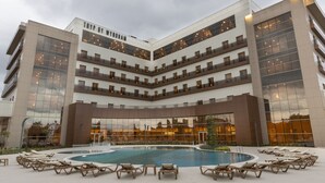 Un hôtel moderne doté d’une piscine centrale, de nombreux balcons et d’une façade en verre réfléchissant.