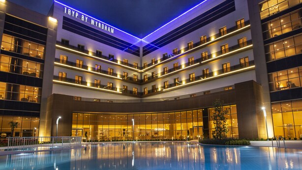 A modern hotel with a central courtyard pool, multiple balconies, and a prominent "TRYP BY WYNDHAM" sign. - TRYP by Wyndham Izmit (Basiskele)