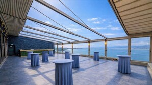 A spacious outdoor terrace with round tables and a view of the sea. - TRYP by Wyndham Izmit (Basiskele)