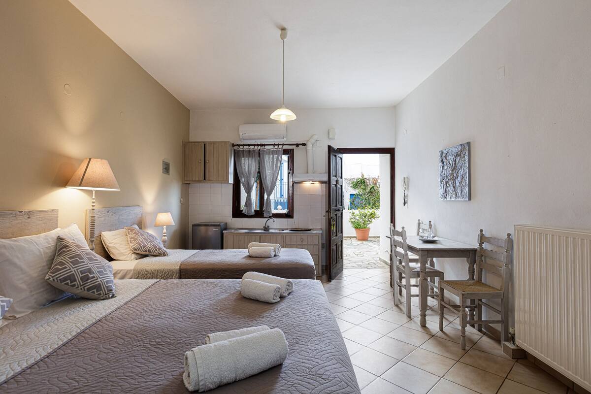 Ein Hotelzimmer mit zwei Betten, einem Esstisch und einer Küchenzeile.