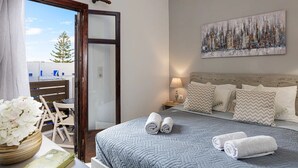 Un dormitorio con cama, almohadas, mesita de noche, lámpara y un cuadro en la pared.
