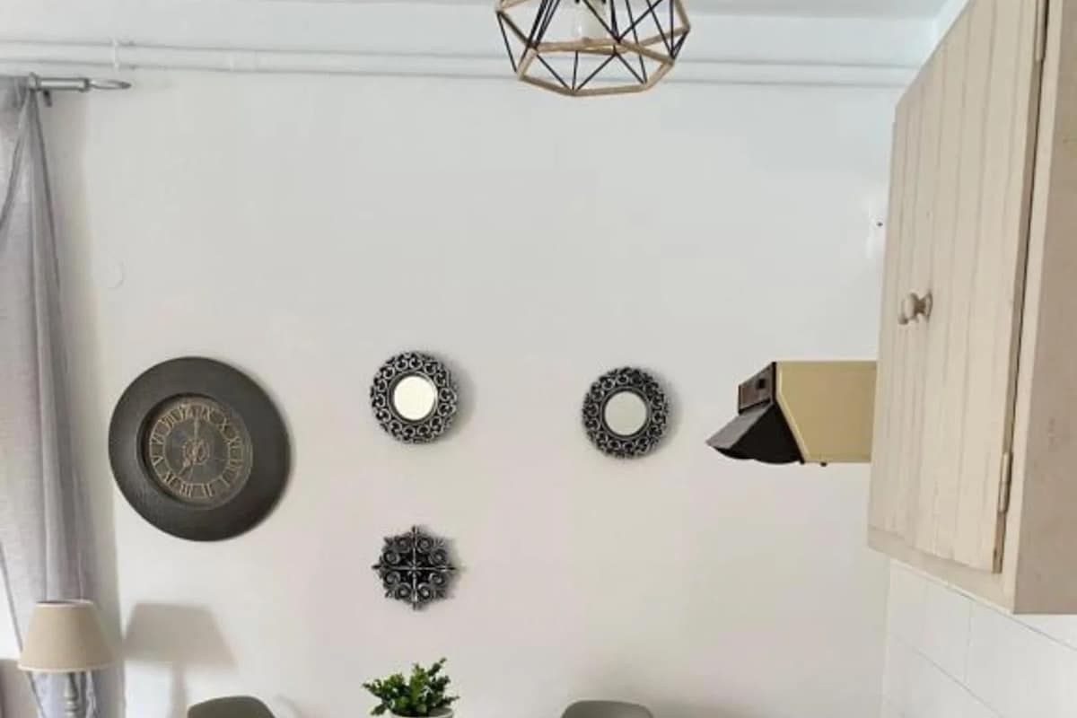 Una cocina compacta con una mesa redonda, dos sillas, un lavamanos y placas decorativas en la pared.