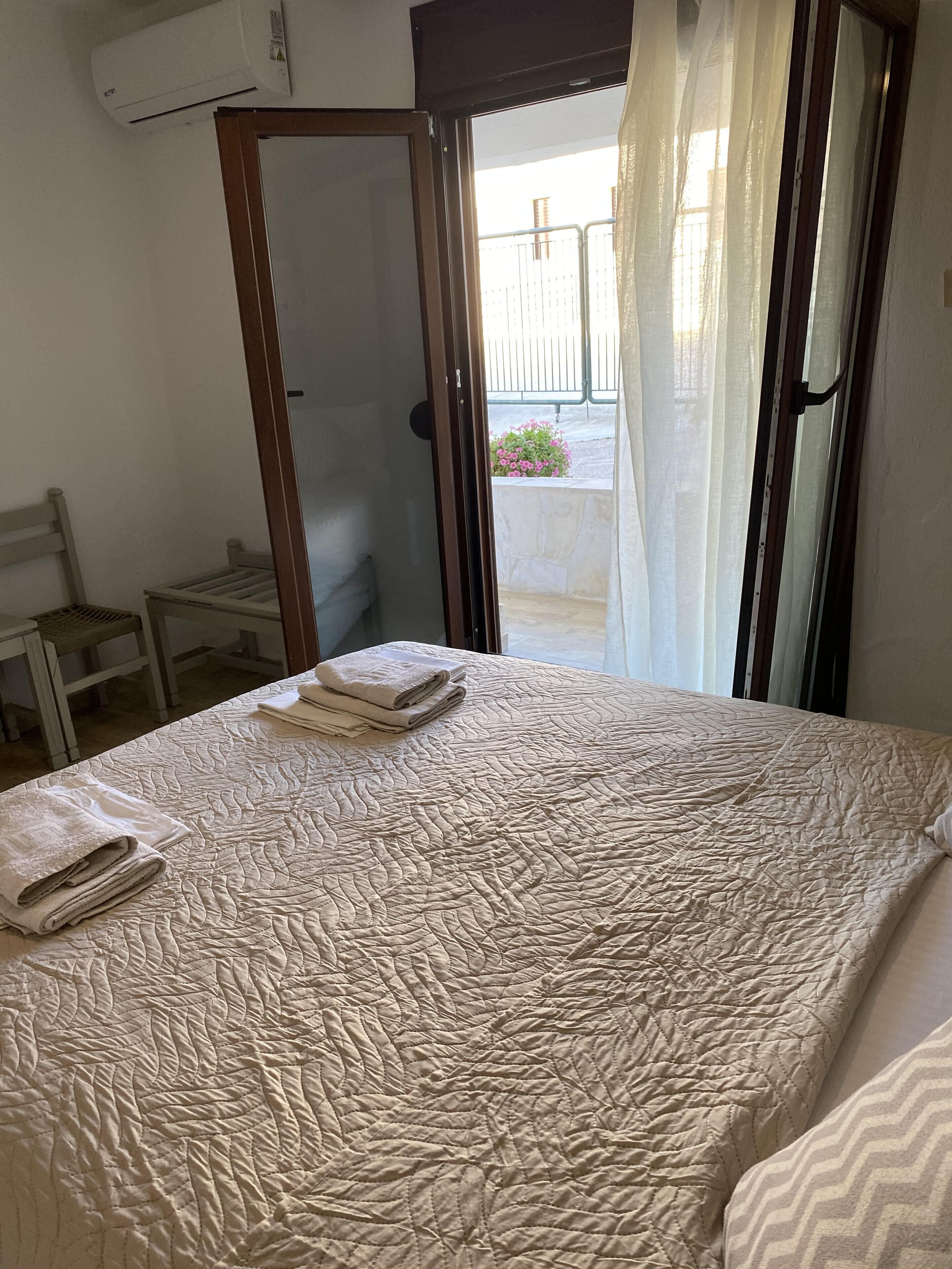 A bedroom with a bed, a chair, and an air conditioning unit.