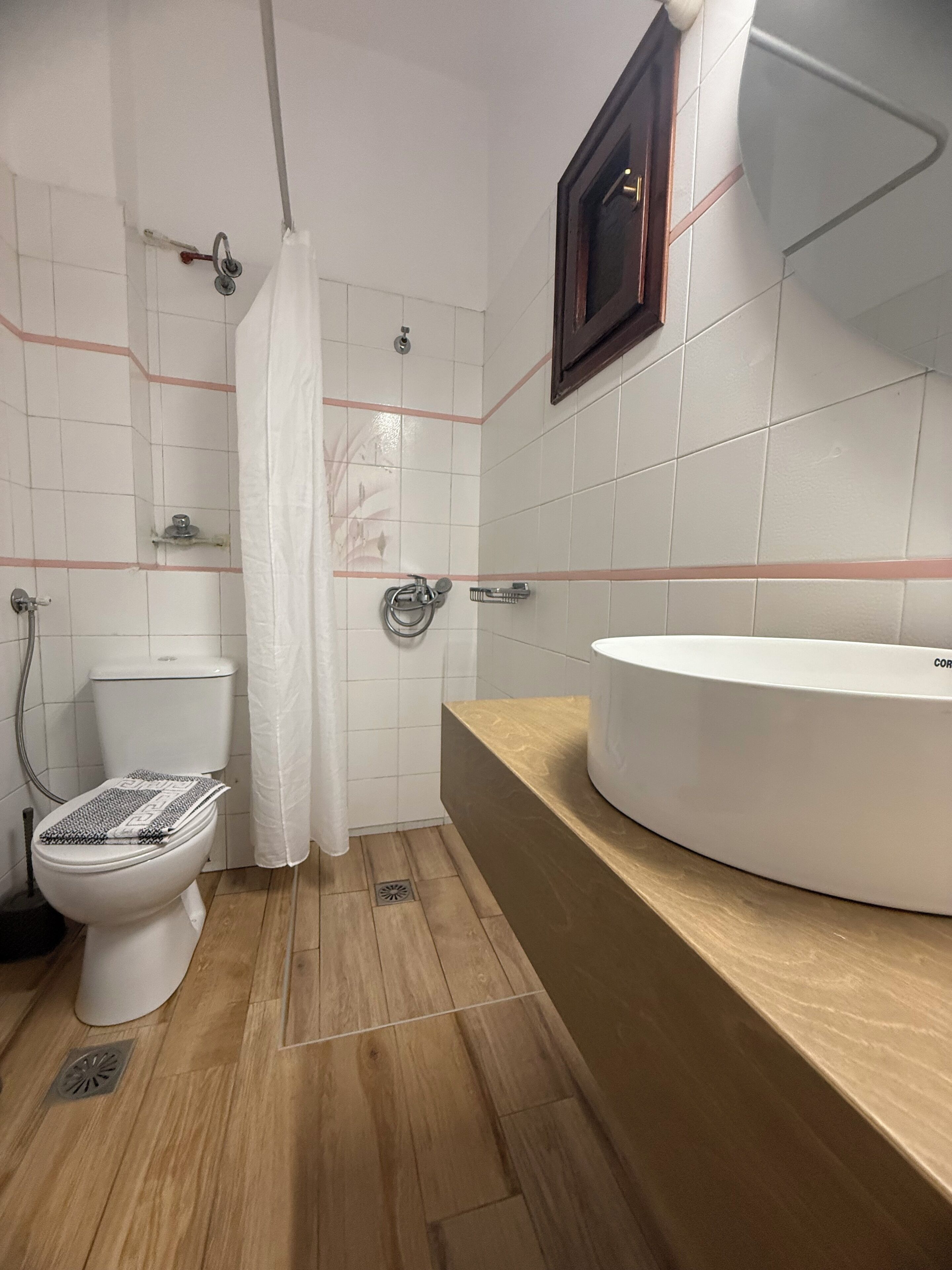 Et badeværelse med toilet, bruser og vask.