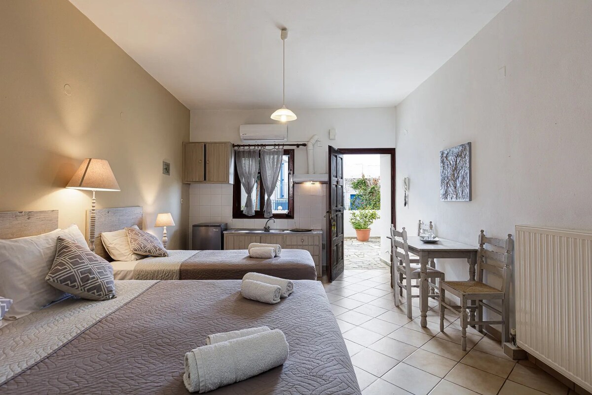 Habitación de hotel con dos camas, kitchenette, zona de comedor y vistas al exterior.