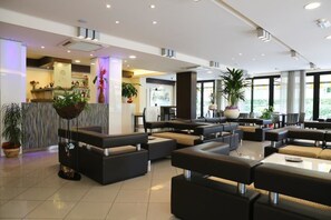 A modern hotel lobby with a reception desk, seating areas, and large windows. - Hotel Ambra (Cesenatico)