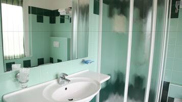 Ein Badezimmer mit Waschbecken, Spiegel und Duschbereich.