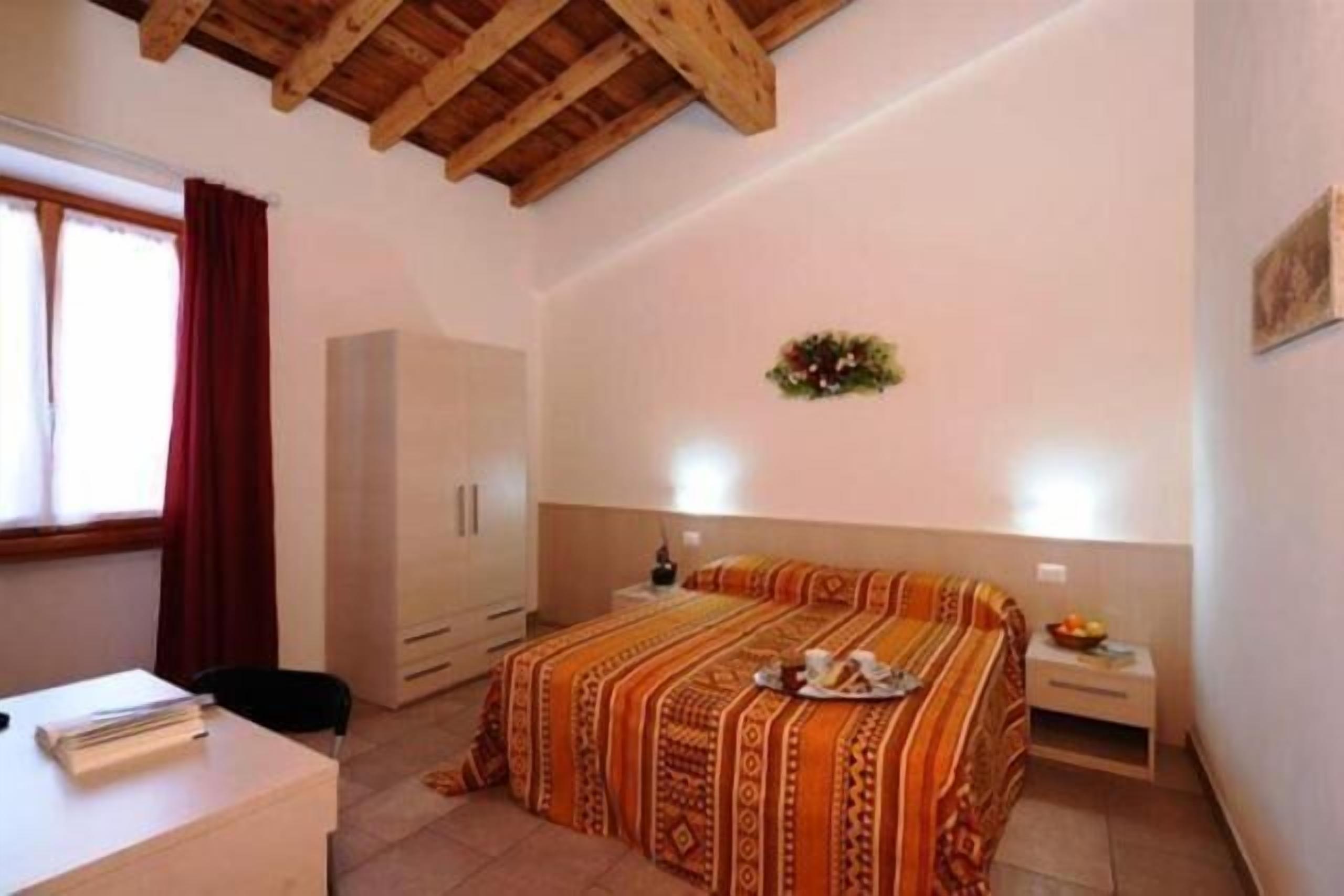 A bedroom with a bed, a desk, and a wardrobe.