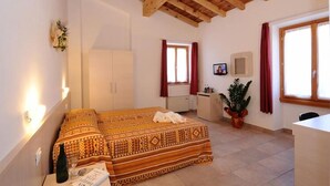 Un dormitorio con cama, escritorio, silla, planta en maceta y ventana con cortinas.