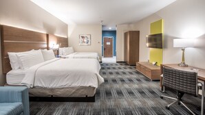 Habitación de hotel con dos camas, un escritorio, una silla, un televisor y una lámpara.